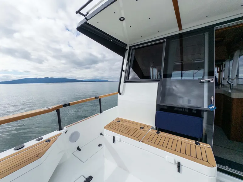 Slide: The Image of 2024 Targa 37 boat deck with wooden seating, overlooking calm waters and cloudy sky. - 24