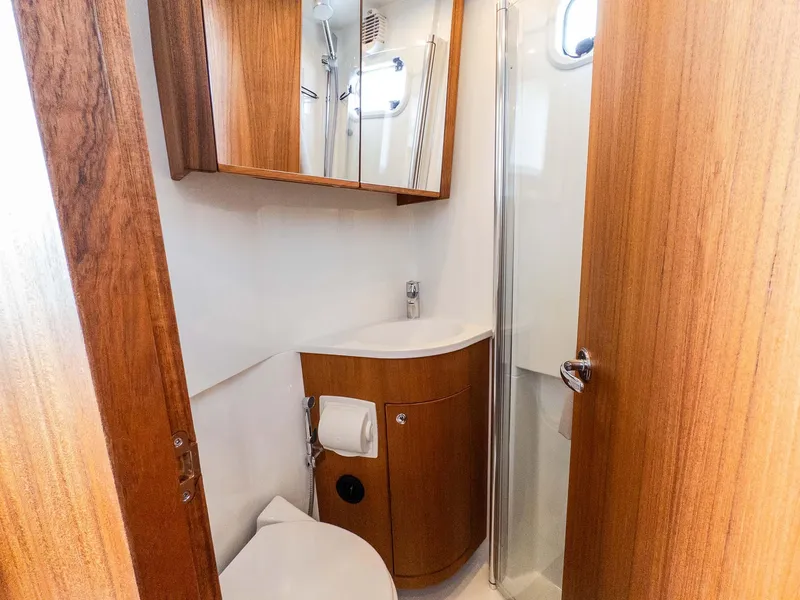 Slide: The Image of 2024 Targa 37 yacht bathroom with wooden cabinetry, compact sink, and shower. - 39
