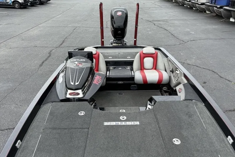 Slide: The Image of 2015 Ranger Z520 Comanche boat interior with red and gray seating, parked on asphalt. - 23