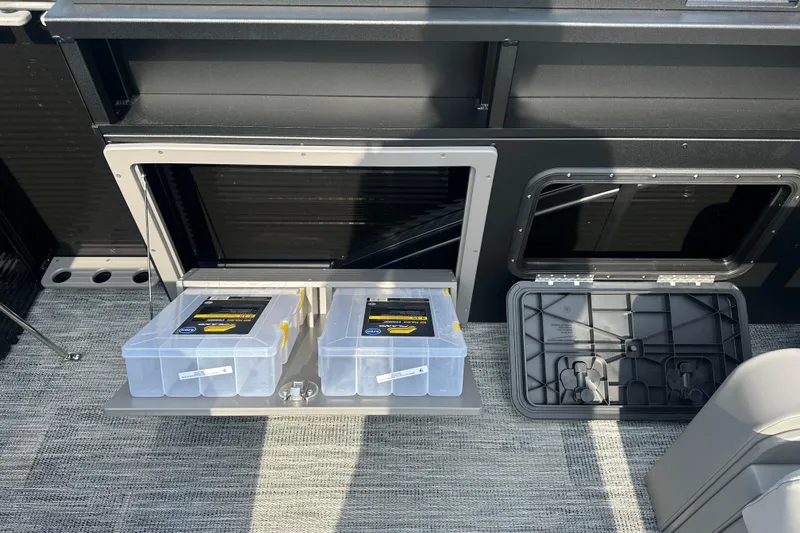 Slide: The Image of Storage compartments on 2026 Qwest M-Class 24 Pro Sport boat, featuring organized plastic containers. - 12