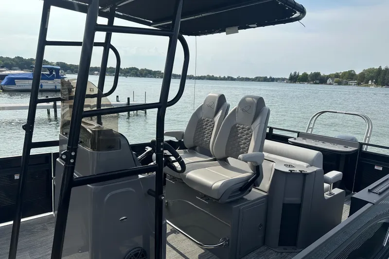 Slide: The Image of 2026 Qwest M-Class 24 Pro Sport boat interior with dual captain seats on a serene lake. - 5