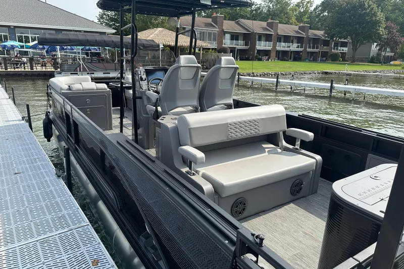 Slide: The Image of 2026 Qwest M-Class 24 Pro Sport pontoon boat docked by waterfront homes. - 7