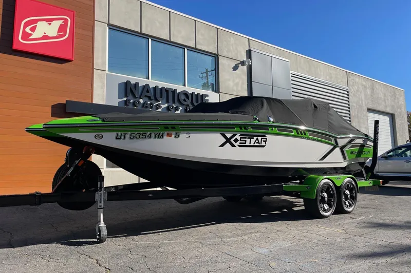 Slide: The Image of 2013 MasterCraft XStar boat on trailer, covered, outside Nautique dealership. - 16