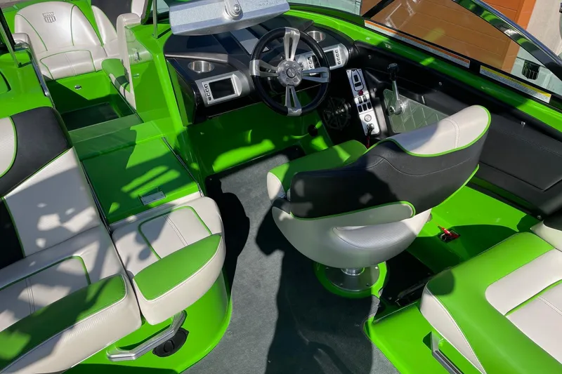 Slide: The Image of 2013 MasterCraft XStar boat interior with green and white seating, modern steering, and controls. - 6