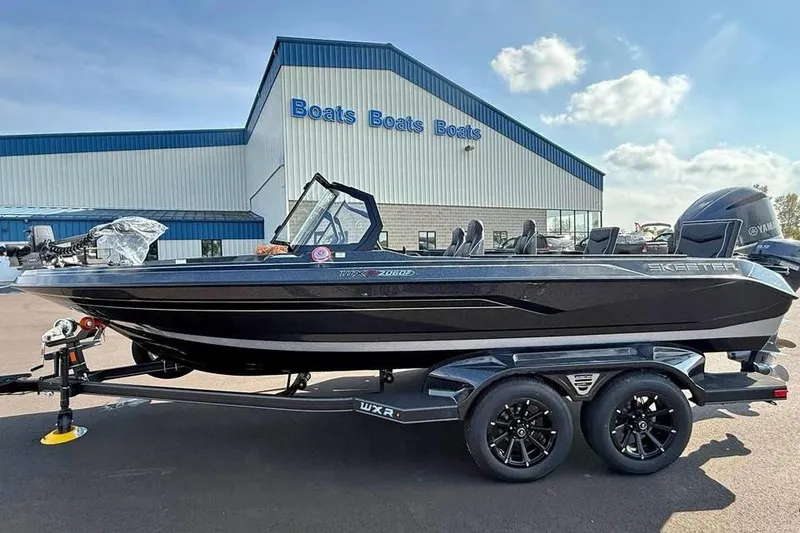 The Image of 2026 Skeeter WXR2060 F boat on trailer outside dealership under blue sky. - 0