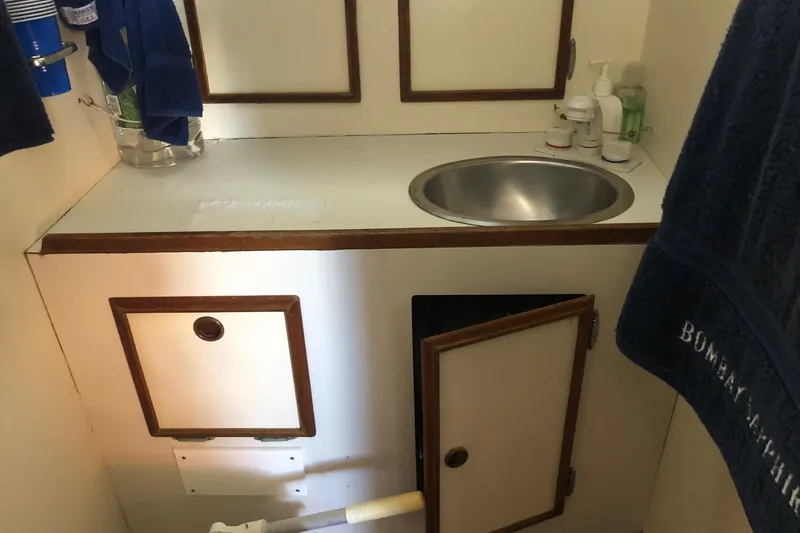 Slide: The Image of 1979 Cape Dory 36 yacht bathroom with sink, storage cabinets, and toiletries. - 12