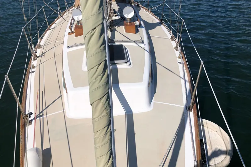 Slide: The Image of 1979 Cape Dory 36 sailboat deck view, featuring rigging and hatch, on calm water. - 19