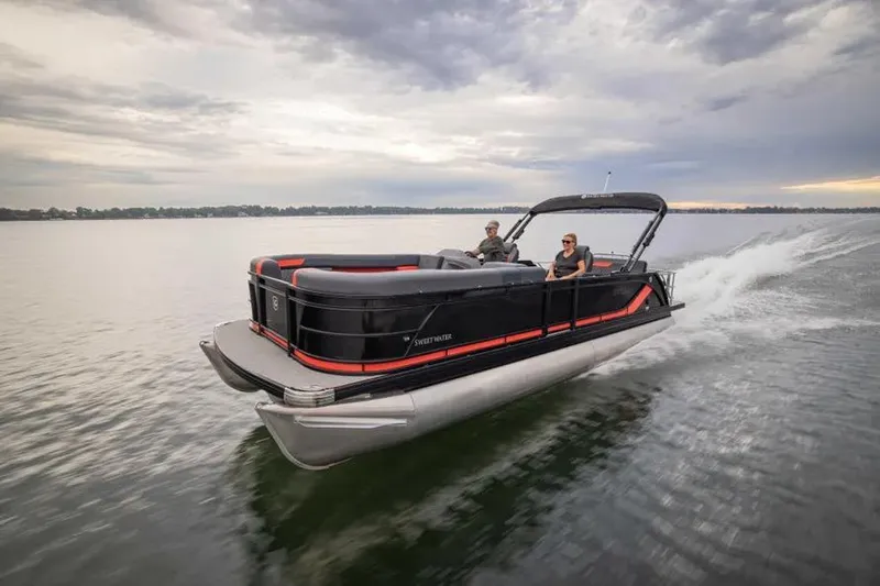 The Image of 2026 Godfrey Sweetwater 22' Split Bench Tritoon cruising on a lake under cloudy skies. - 1