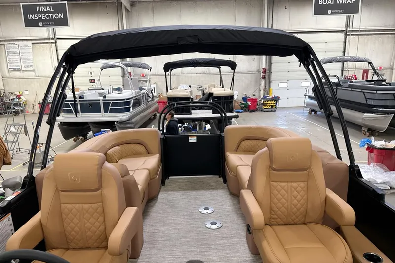 Slide: The Image of Interior of 2026 Godfrey Sweetwater 22' Tritoon with luxurious tan seating in a showroom. - 12