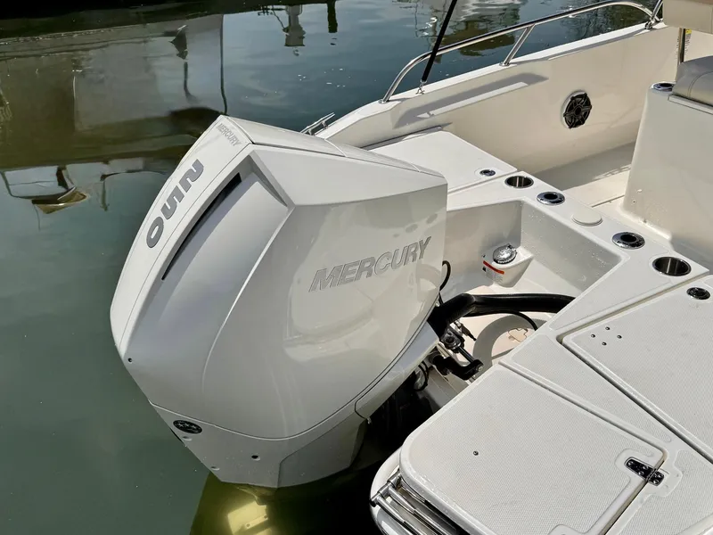 Slide: The Image of 2022 Boston Whaler 220 Dauntless with Mercury outboard engine, docked on calm water. - 10