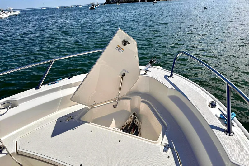 Slide: The Image of 2022 Boston Whaler 220 Dauntless boat with open storage compartment on calm water. - 12