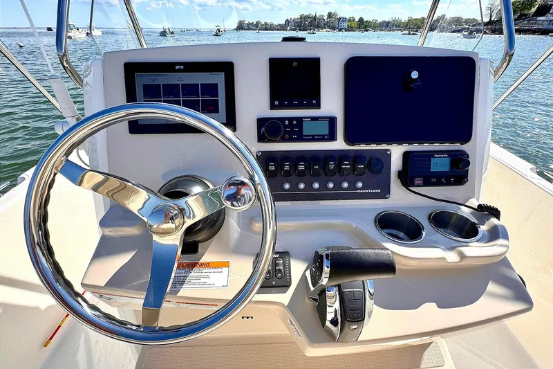Slide: The Image of Boston Whaler 220 Dauntless 2022 helm with steering wheel and control panel on open water. - 2