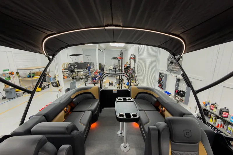 Slide: The Image of 2026 Godfrey Sweetwater 22' Tritoon interior with split bench seating in a workshop. - 32