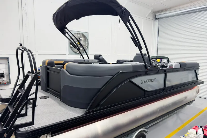 Slide: The Image of 2026 Godfrey Sweetwater 22' Split Bench Tritoon in a showroom, featuring sleek design and modern amenities. - 4