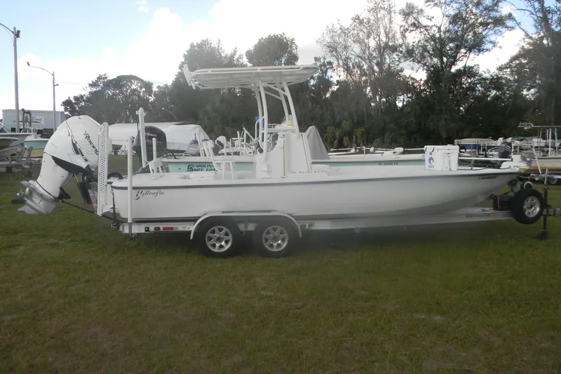 The Image of 2013 Yellowfin 24 Bay boat on trailer, parked on grass with trees in background. - 1