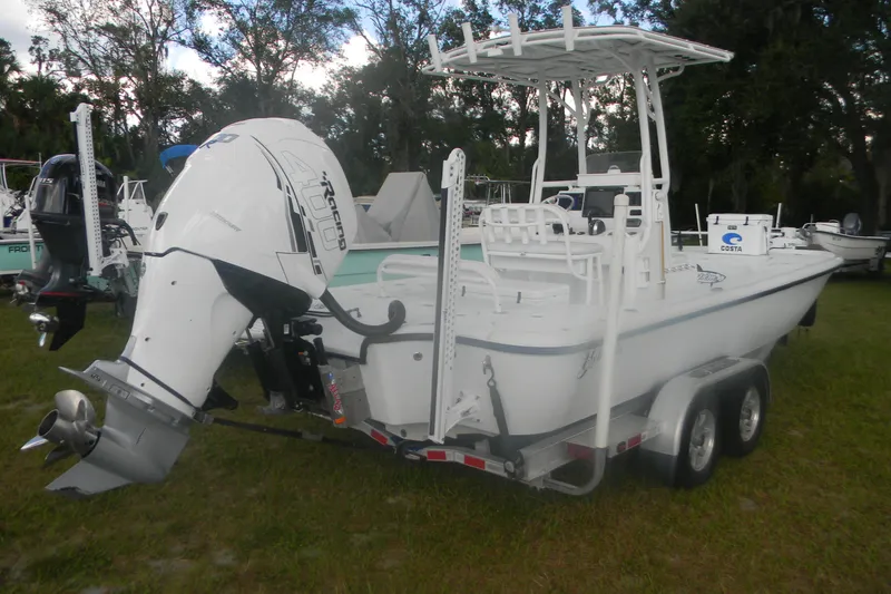 Slide: The Image of 2013 Yellowfin 24 Bay boat with powerful outboard motor on trailer, parked on grass. - 4