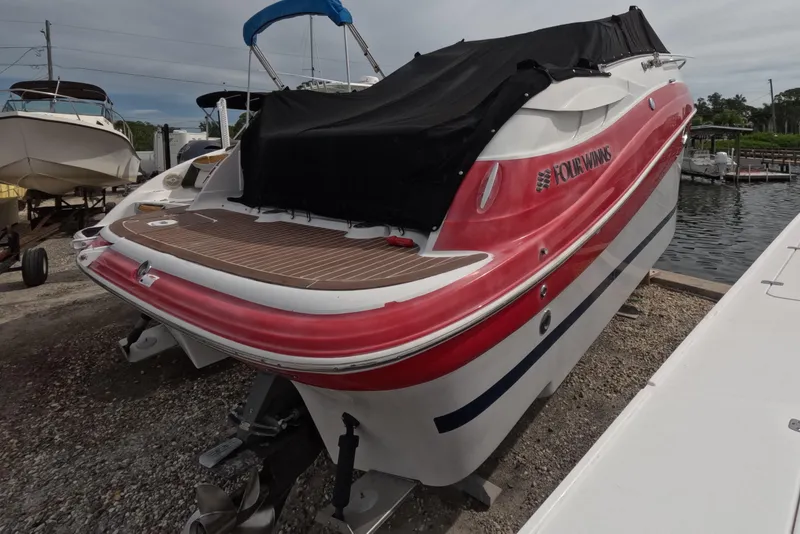 Slide: The Image of 2012 Four Winns V265 boat with red and white exterior, docked near water. - 11