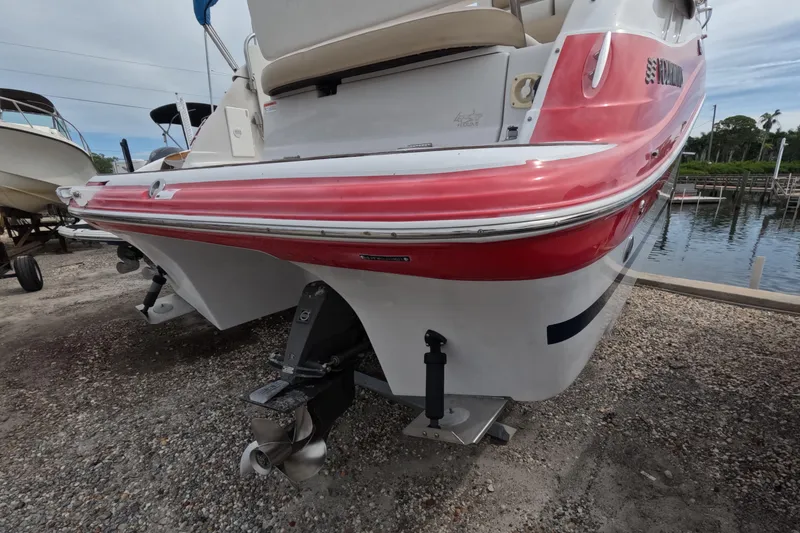 Slide: The Image of 2012 Four Winns V265 boat with red and white hull, docked on gravel. - 13