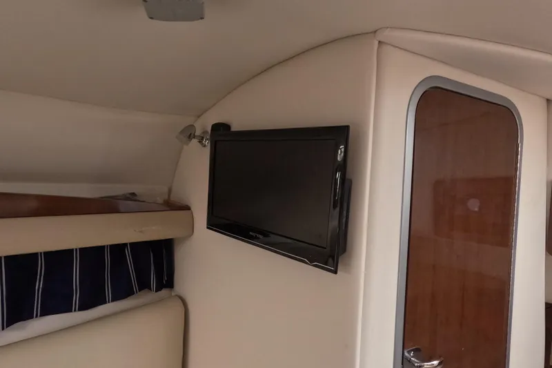 Slide: The Image of Interior of 2012 Four Winns V265 boat with mounted TV and wooden door. - 56