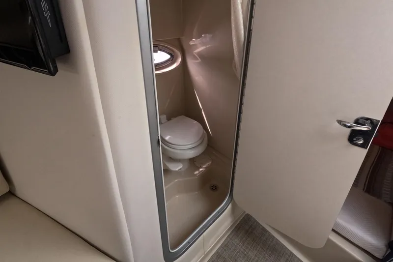 Slide: The Image of 2012 Four Winns V265 boat bathroom with compact toilet and porthole window. - 58