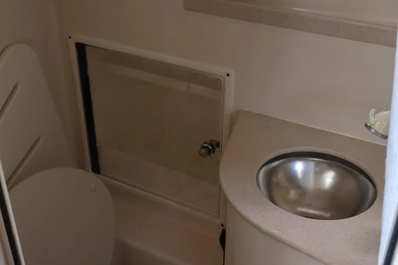 Slide: The Image of Compact bathroom in 2006 Pursuit 3070 Offshore boat with sink and toilet. - 24