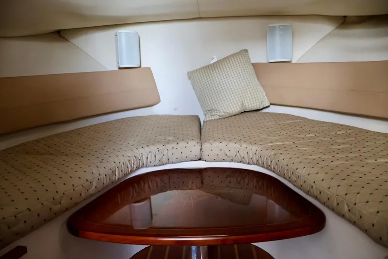 Slide: The Image of 2006 Pursuit 3070 Offshore cabin interior with cushioned seating and wooden table. - 25