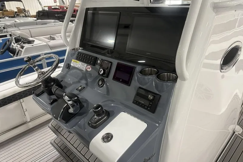 Slide: The Image of 2025 Tidewater 3100 Carolina Bay boat console with steering wheel and dual screens. - 33
