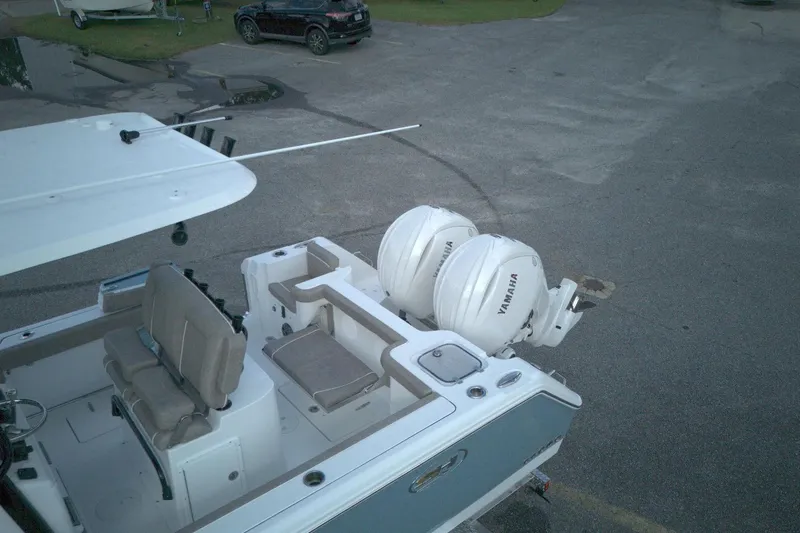 Slide: The Image of 2026 Sea Hunt Gamefish 25 boat with dual Yamaha engines, parked on pavement. - 4