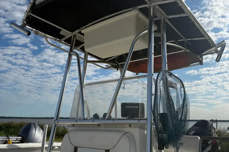 Slide: The Image of 2008 Carolina Skiff 218 DLV boat with T-top and fishing net, under a partly cloudy sky. - 4