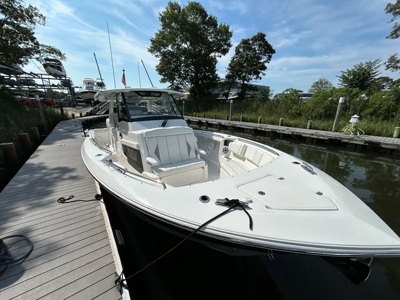 Slide: The Image of 2026 Pursuit S 358 boat docked on a sunny day, surrounded by trees and calm water. - 21
