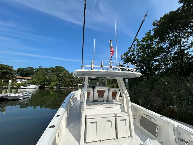 Slide: The Image of 2026 Pursuit S 358 boat docked on a serene lake under a clear blue sky. - 6