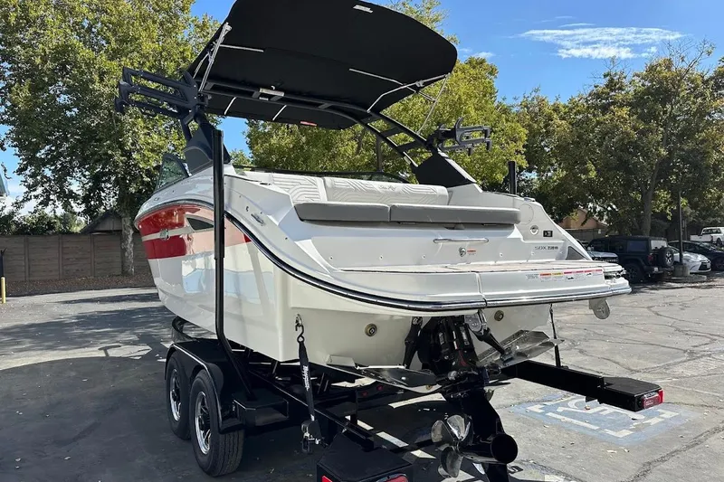 Slide: The Image of 2026 Sea Ray SDX 230 Surf boat on trailer, parked outdoors under clear sky. - 10
