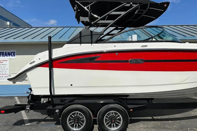 Slide: The Image of 2026 Sea Ray SDX 230 Surf boat on trailer, red and white design, parked outdoors. - 7