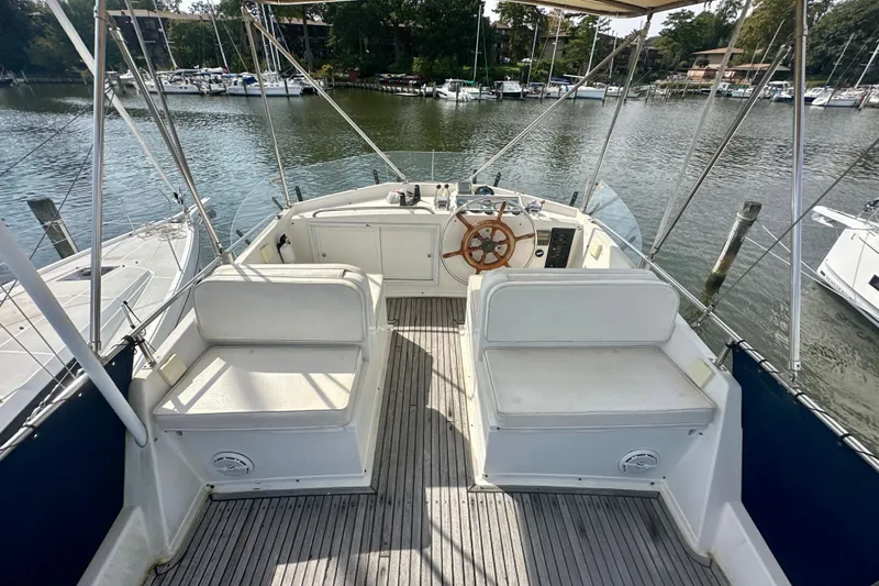Slide: The Image of Flybridge of 1988 Grand Banks 36 Classic yacht with seating and steering wheel, docked by the water. - 15