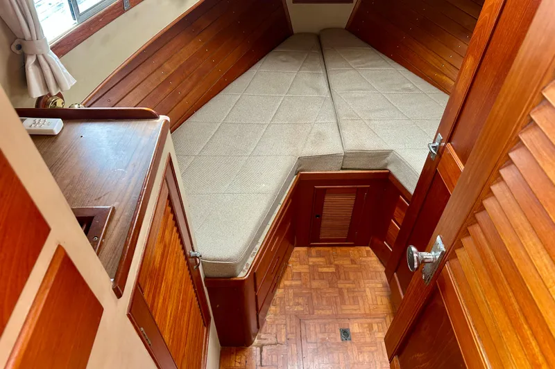 Slide: The Image of 1988 Grand Banks 36 Classic cabin interior with wood paneling and cushioned V-berth. - 31