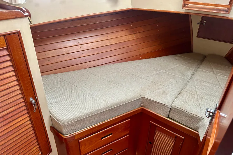 Slide: The Image of 1988 Grand Banks 36 Classic cabin interior with wooden paneling and cushioned berth. - 32