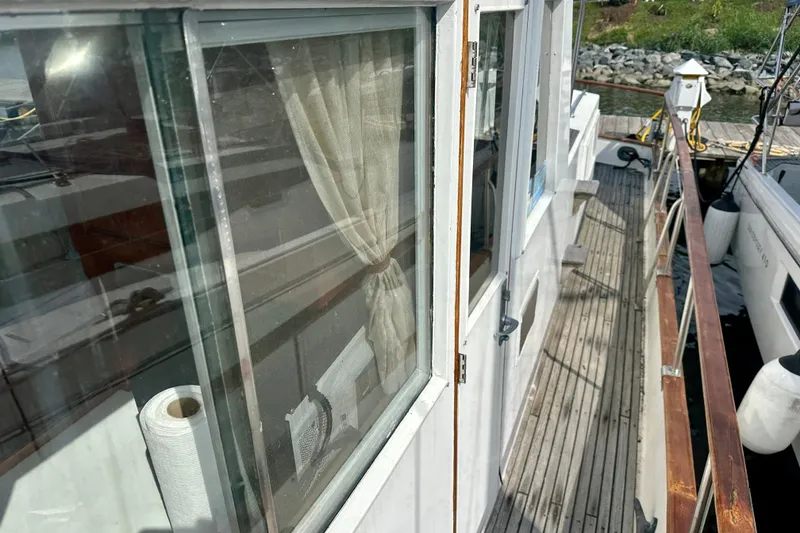 Slide: The Image of 1988 Grand Banks 36 Classic yacht deck with wooden railings and window view. - 7