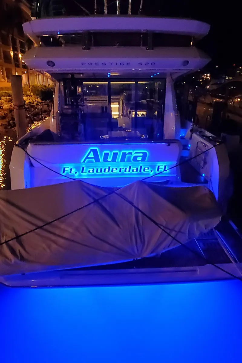 Slide: The Image of Prestige 520 yacht, 2018 model, named "Aura," docked in Fort Lauderdale, illuminated at night. - 48