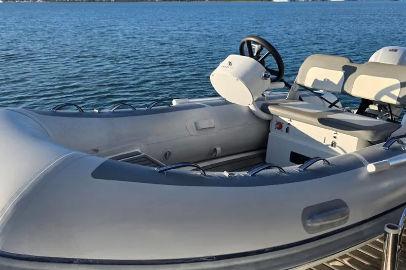 Slide: The Image of 2023 Lagoon 50 inflatable boat on calm water, featuring steering wheel and seating. - 18