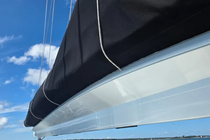 Slide: The Image of 2023 Lagoon 50 sailboat with black sail cover against blue sky. - 23