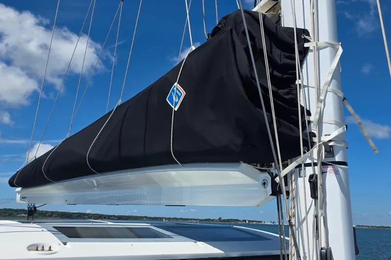 Slide: The Image of 2023 Lagoon 50 sailboat mast with black sail cover under blue sky. - 24