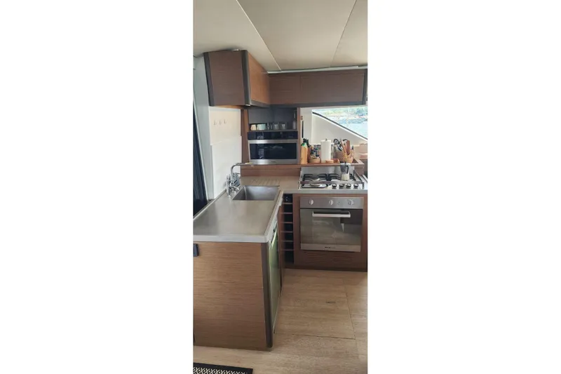 Slide: The Image of Modern kitchen interior on 2023 Lagoon 50 yacht, featuring sleek appliances and wooden cabinetry. - 34