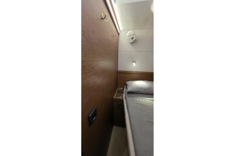 Slide: The Image of 2023 Lagoon 50 yacht interior cabin with wooden paneling and cozy bed. - 53