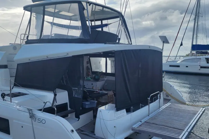Slide: The Image of 2023 Lagoon 50 catamaran docked at marina, featuring covered deck and modern design. - 6