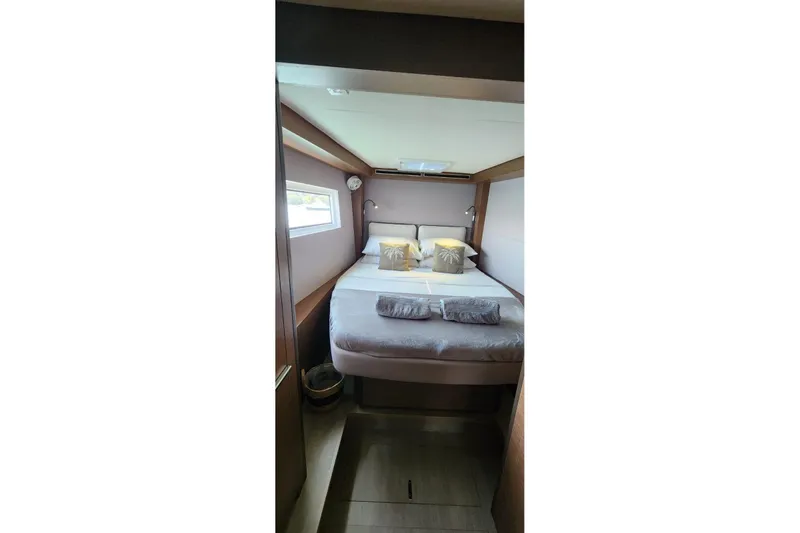 Slide: The Image of 2023 Lagoon 50 yacht cabin with cozy bed, pillows, and window view. - 65