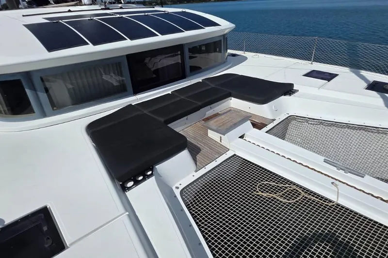 Slide: The Image of 2023 Lagoon 50 catamaran deck with seating and netting, overlooking blue water. - 7
