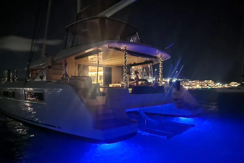 Slide: The Image of 2023 Lagoon 50 yacht illuminated at night with blue underwater lights. - 85