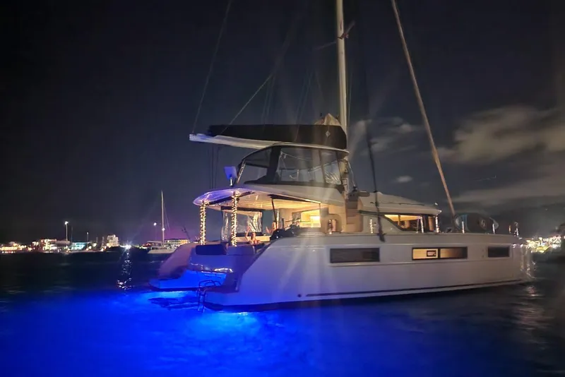 Slide: The Image of 2023 Lagoon 50 catamaran illuminated at night with blue underwater lights. - 86