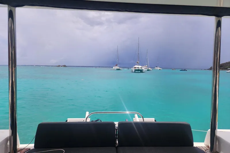 Slide: The Image of View from Lagoon 50 catamaran, 2023 model, overlooking turquoise sea and anchored sailboats. - 88