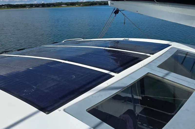 Slide: The Image of 2023 Lagoon 50 yacht with solar panels on deck, overlooking serene water. - 9